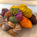 A small pile of deeply colored thick yarn resting on a wood backround